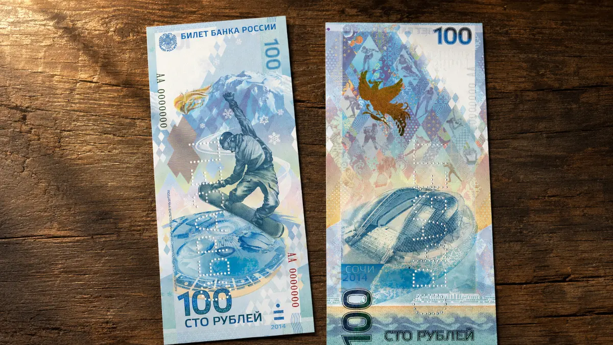 Лицевая сторона памятной банкноты 100 рублей Сочи 2014 — сноубордист в прыжке, Кавказские горы и прибрежные олимпийские объекты